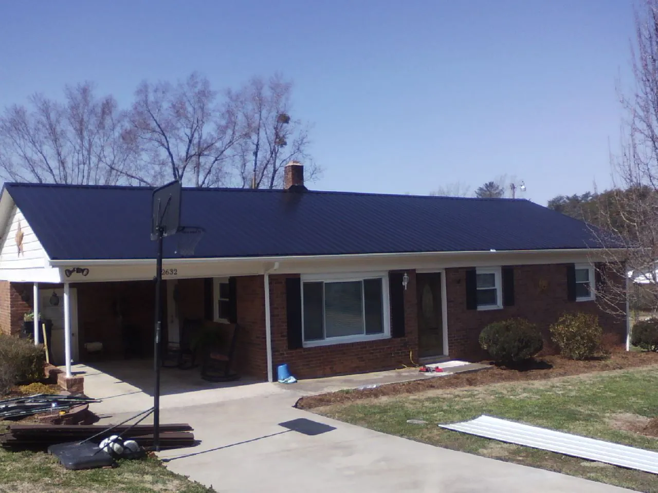 Finished dark blue metal roof on a brick ranch with a carport in Harrisville